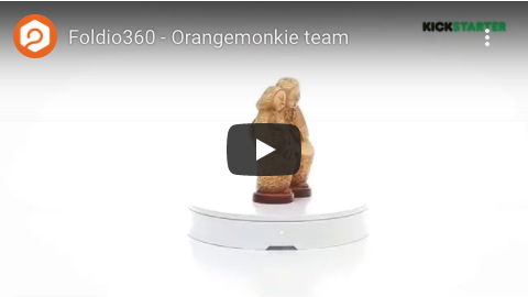 Ein Foldio360-Video des Orangemonkie-Teams zeigt eine rotierende Plattform mit einer kleinen, geschnitzten Statue einer sitzenden Figur. Das Kickstarter-Logo befindet sich in der oberen rechten Ecke.
