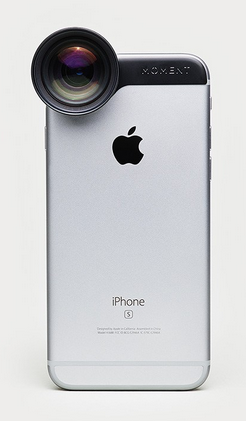 Ein silbernes iPhone mit schwarzem Objektivaufsatz ist von hinten zu sehen. Das Objektiv befindet sich über der oberen linken Ecke, in der Nähe der Kamera, und trägt die Aufschrift „MOMENT“. Das Apple-Logo und der Modellname „iPhone“ sind auf dem Telefon sichtbar.
