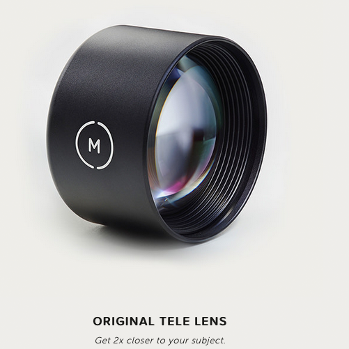Ein schwarzes Teleobjektiv mit einem „M“-Logo an der Seite ist aus nächster Nähe vor einem weißen Hintergrund zu sehen. Reflektierende Elemente des Objektivs sind sichtbar. Der Text darunter lautet: „ORIGINAL-TELEOBJEKTIV – Kommen Sie 2x näher an Ihr Motiv heran.“