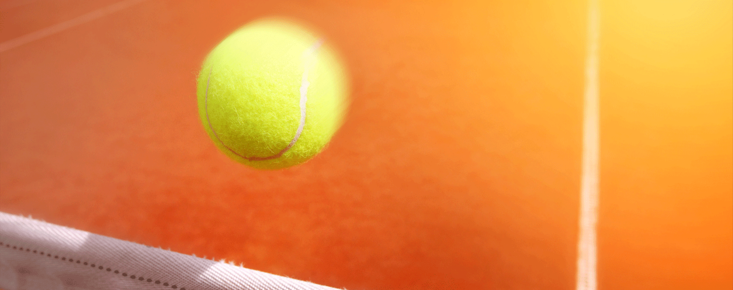 Eine Nahaufnahme eines leuchtend gelben Tennisballs, der in der Luft über einem Netz auf einem sonnenbeschienenen Tennisplatz fliegt. Der Hintergrund ist ein Farbverlauf in Orangetöne. Der Fokus liegt auf dem Ball, wobei das Netz und die Spielfeldlinien leicht unscharf sind.