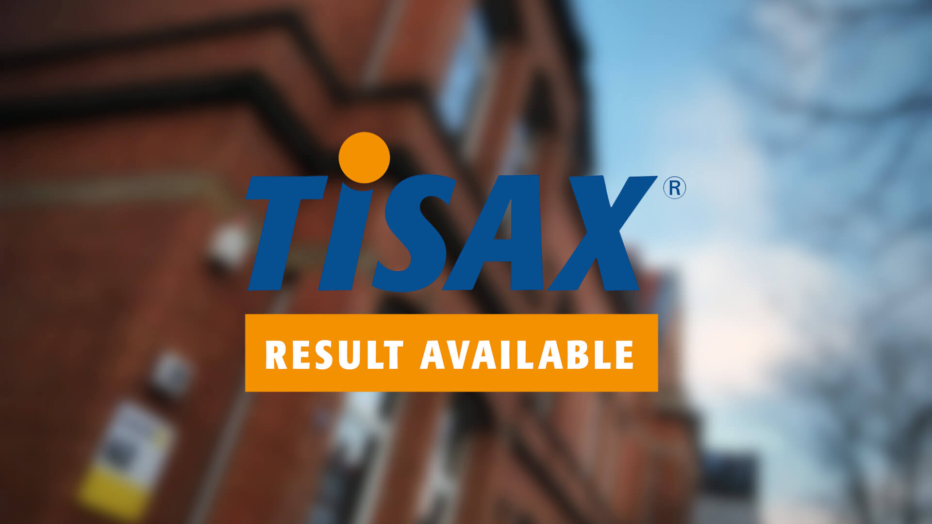 Ein unscharfer Hintergrund eines Backsteingebäudes mit dem TISAX Logo im Vordergrund.